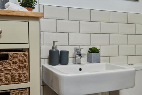 达宁顿堡Delven House, Apartment 3的浴室铺有白色瓷砖,配有白色水槽。