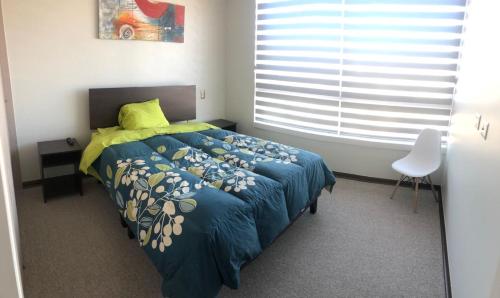 科金博Departamento Familiar con vista al Mar的一间卧室配有一张带蓝色棉被的床和窗户。
