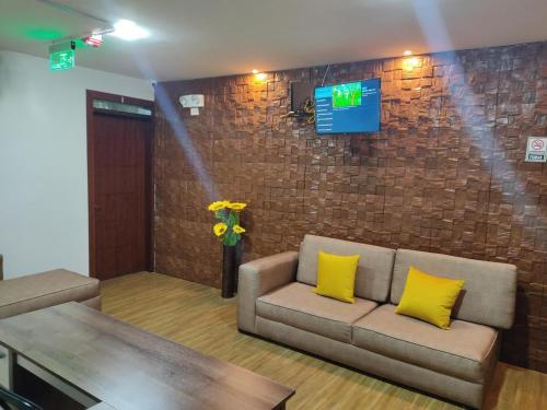 基多Hospedaje El Girasol TABABELA的客厅配有沙发和砖墙电视