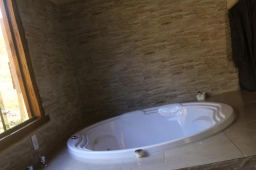 维奥康德马奥Pousada Leal Chalé的带浴缸的浴室和砖墙