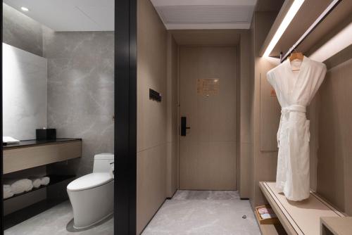 杭州杭州礼顿酒店（ 所有房型入住均赠送软饮）的浴室的白色长袍挂在门上
