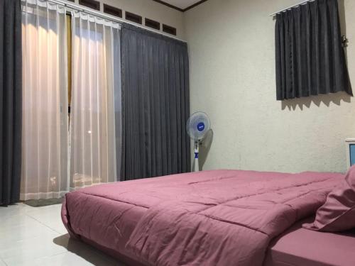 庞岸达兰Saung Rancage Batukaras的卧室配有粉红色的床和风扇。