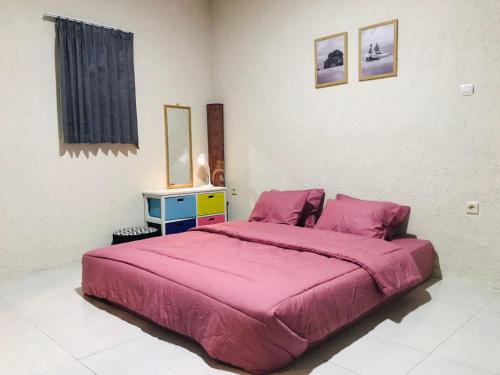 庞岸达兰Saung Rancage Batukaras的一间卧室配有一张带粉色毯子的大床