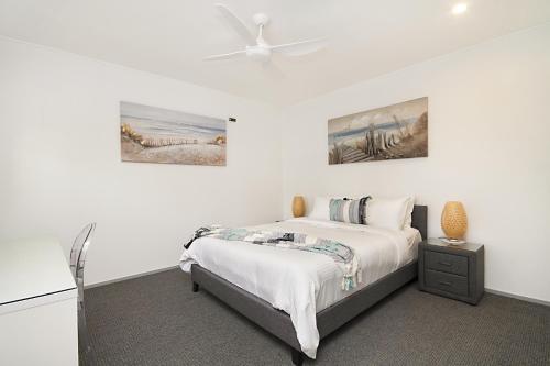 金斯克里福Spacious 3 bedroom apartment opposite surf club的白色卧室配有床和吊扇