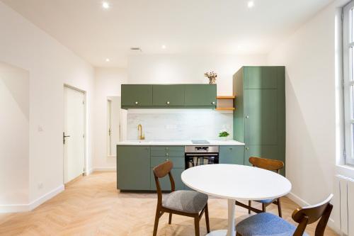 阿尔勒La Nuit Arlésienne - Exclusive apartments的厨房配有绿色橱柜和桌椅
