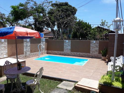 里约达欧特拉斯Ótima casa de praia com piscina的一个带遮阳伞的庭院内的游泳池