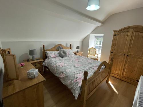CullybackeyRose Cottage的一间卧室配有一张床和一个木制梳妆台