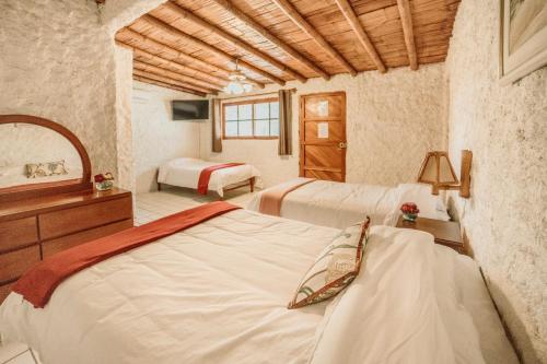 伊察Hotel Fundo El Arrabal的一间卧室配有两张床、一个梳妆台和镜子