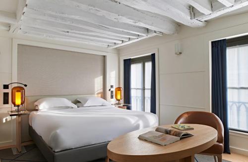 巴黎里什庞斯歌剧院酒店的卧室配有一张白色的大床和一张桌子