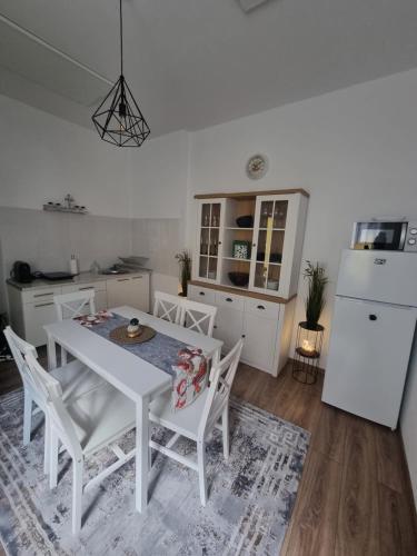 布拉索夫Celebrity Apartment Brasov的厨房配有白色的桌椅和冰箱。