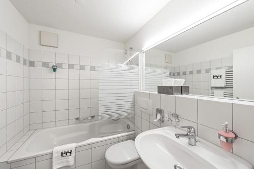 斯德勒基赫斯臣酒店的带浴缸、盥洗盆和卫生间的浴室