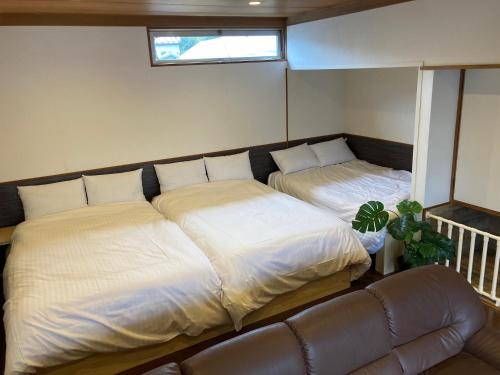 大石Koya TRIBE - Vacation STAY 83407v的一张沙发和一个窗户的客房内的两张床
