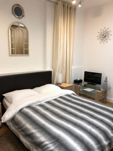 特威克纳姆Modern Apartment in Twickenham Highstreet的一间卧室配有一张大床和电视