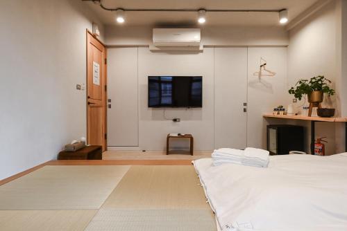 台南Humanlive的卧室配有一张床,墙上配有电视。