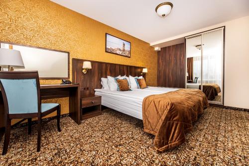 帕兰加Gradiali Wellness and SPA的酒店客房设有一张大床和一张书桌。