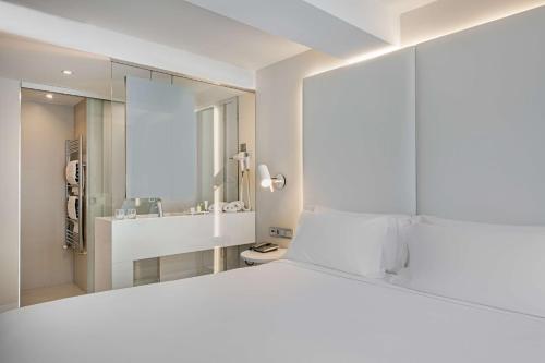 马德里帕萨奥哈瓦那NH酒店的白色的卧室配有一张白色的大床和镜子