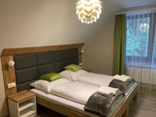 拉达瓦Leśna Polana的一间卧室配有带白色床单和绿色枕头的床。