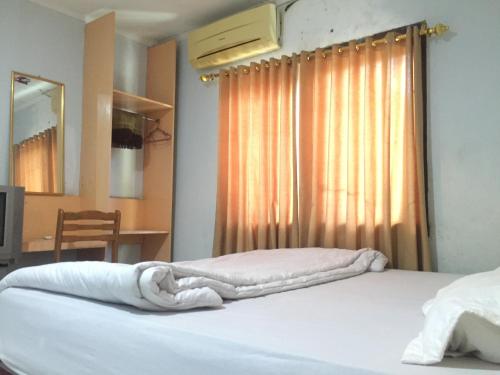沙璜Losmen PUM Syariah at Desa Wisata Sabang的一间卧室配有一张带白色床单的床和一扇窗户。