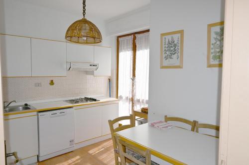 巴多尼奇亚Bardonecchia Appartamento XL的厨房配有白色橱柜和桌椅