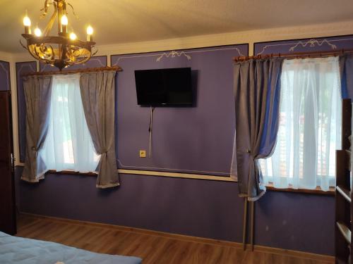 科普里夫什迪察Тороманова къща的一间卧室设有紫色的墙壁和窗帘,配有电视