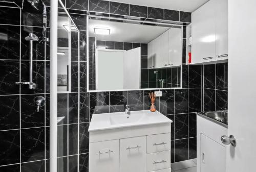 玛志洛太平洋天堂公寓酒店的黑色瓷砖浴室设有水槽和镜子