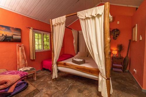 Chilibre巴拿马猴子山林小屋住宿加早餐旅馆的一间卧室设有天蓬床和橙色墙壁。