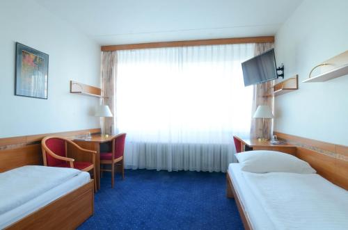 布拉格ILF酒店的客房设有两张床、一张桌子和一个窗户。