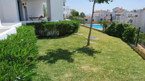 阿尔加德萨Apartamento 6 persona en la Alcaidesa的种有草和植物的院子和游泳池