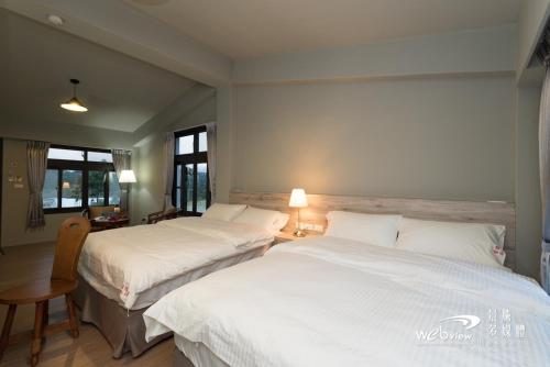 鹿野笔拉民宿的配有白色床单的酒店客房内的两张床