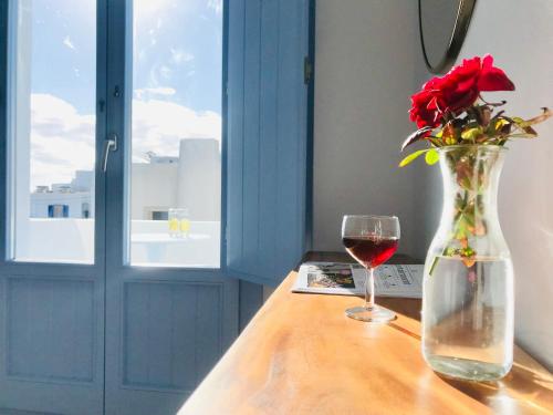 菲罗斯特法尼佛蒂尼别墅酒店的花瓶里放着红玫瑰和一杯葡萄酒