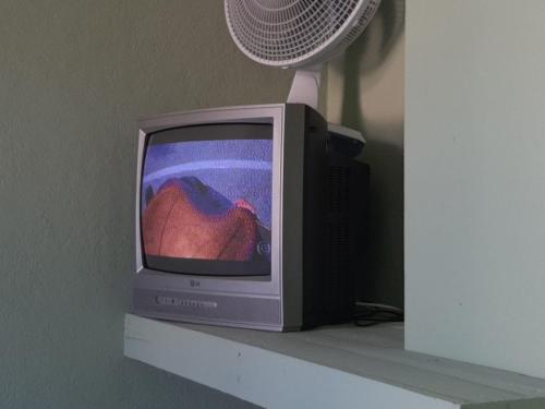 圣托梅-达斯莱特拉斯Palácio do Sol Hostel Pousada的旧电视,放在带风扇的架子上