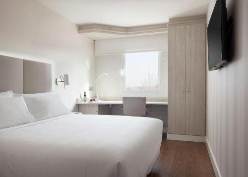 马德里巴拉哈斯机场NH酒店 的卧室配有一张白色大床和一张书桌