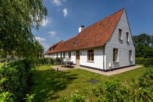 奥斯特坎普Loweide Lodges & Holiday Homes near Bruges的一座白色的大建筑,有红色的屋顶
