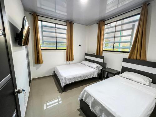 阿瓜奇卡Sagrado Hotel的带两张床和两个窗户的房间