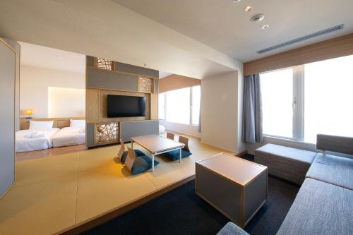 别府AMANEK Beppu YULAｰRE的酒店客房配有床、沙发和电视。
