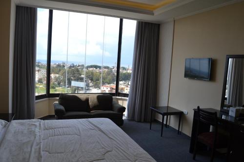 提尔白金酒店 的酒店客房设有一张床铺、一把椅子和一个大窗户。