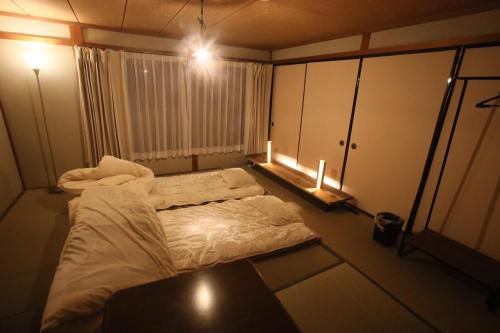下吕市コミュニティカフェ民泊つむぎ的小房间设有床、桌子和灯
