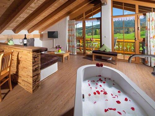 比绍夫斯维森Ferienwohnung Roislerlehen的客厅设有浴缸,内配红色鲜花