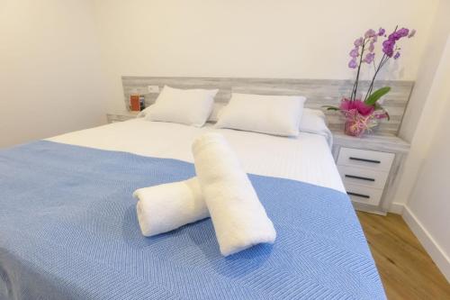 利亚内斯Apartamentos Centro Llanes的一张带两个白色枕头和蓝色毯子的床