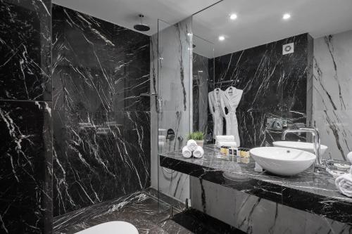 班斯科Grand Hotel Bansko - Fitness & SPA的黑色大理石浴室设有水槽和镜子