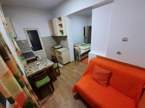 索科矿泉村Smeštaj Milenković的一间带橙色沙发的客厅和一间厨房