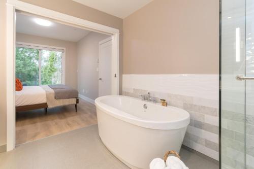 苏克Coffee With A View, Brand New One Bedroom At Sooke Harbour的带浴缸的白色浴室和卧室