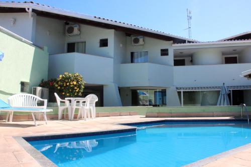 塞古罗港Hotel Ponta de Areia的一座带两把椅子的游泳池以及一座建筑