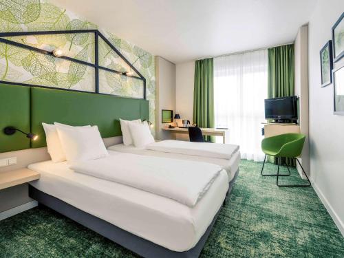 汉诺威汉诺威米特美居酒店的酒店客房设有两张床和绿色的墙壁。