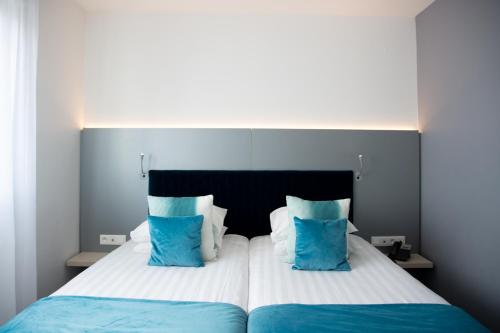 科尔马科尔马酒店 的一间卧室配有一张带蓝白色枕头的大床