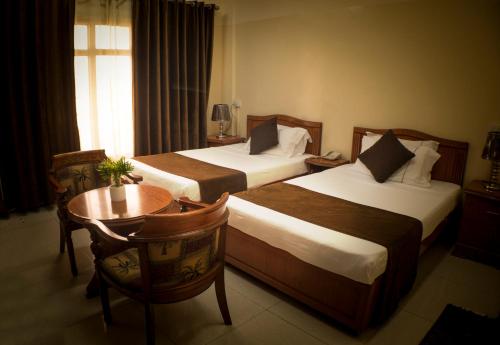 吉布提Comfort Hotel的酒店客房设有两张床、一张桌子和一张书桌。