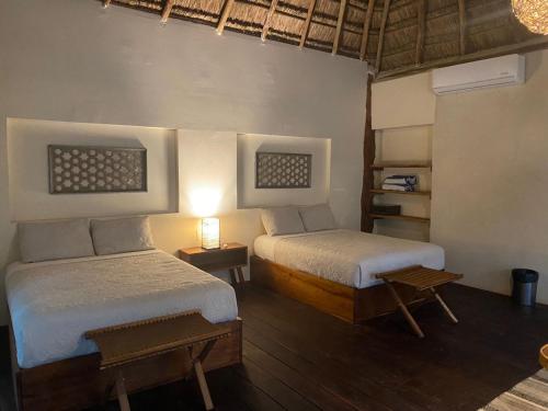 巴卡拉尔Xoot Ka’Ana villa fantasía的一间卧室配有两张床、一张桌子和一盏灯。
