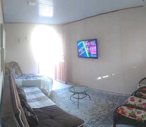 弗洛里亚诺波利斯Casa barreto的客厅配有沙发和墙上的电视
