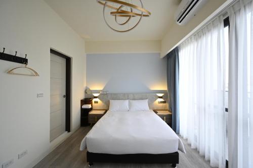 台南台南安平 - 理蓄豪宅 - 可加價Ktv及烤肉的卧室设有白色的床和大窗户