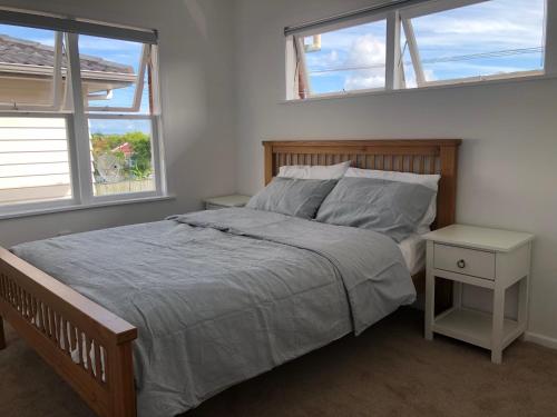 奥克兰Comfortable Holiday Home at Mt Wellington的一间卧室设有一张大床和两个窗户